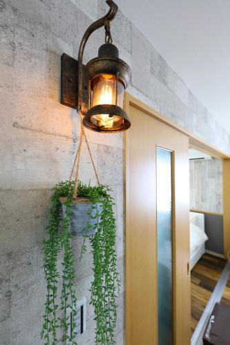 a light hanging from a wall with a potted plant at Prosper 6th bldg in Nagoya