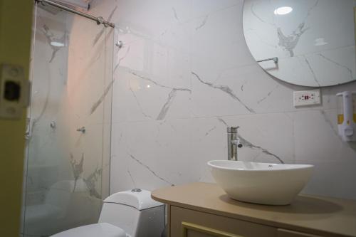 łazienka z umywalką, toaletą i lustrem w obiekcie Hotel Chromatic w mieście Guatapé