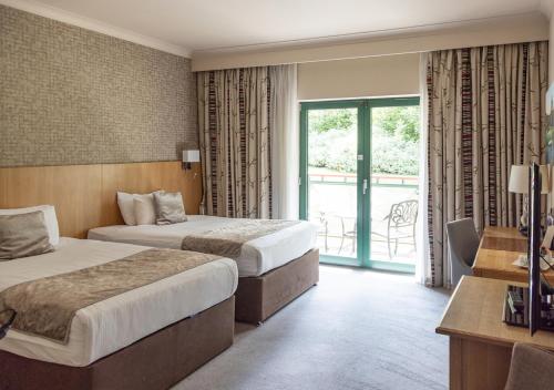 a hotel room with two beds and a balcony at Vale Resort in Hensol