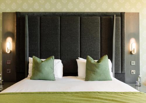 a bedroom with a large bed with green and white pillows at Vale Resort in Hensol