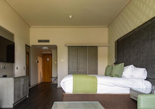a bedroom with a large white bed and a kitchen at Vale Resort in Hensol