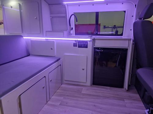 a small kitchen with white cabinets and a mirror at Autocaravana Camper in Las Palmas de Gran Canaria