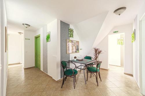 a dining room with a table and green chairs at Charlie Vendégház in Sé