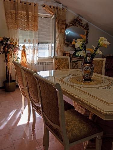 a dining room table with chairs and a vase on it at "Da Remo" in Mògoro