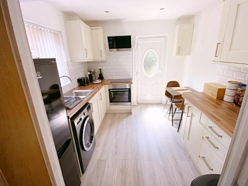 a kitchen with white cabinets and a washer and dryer at The Serene Stays Sleeps 6 with Garden in Oldham