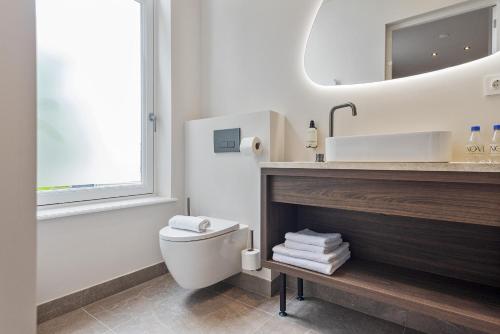 a bathroom with a toilet and a sink and a mirror at Boutique hotel Novi in Zandvoort