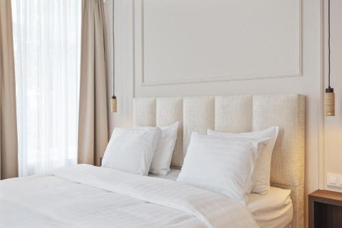 a bed with white sheets and pillows next to a window at Boutique hotel Novi in Zandvoort