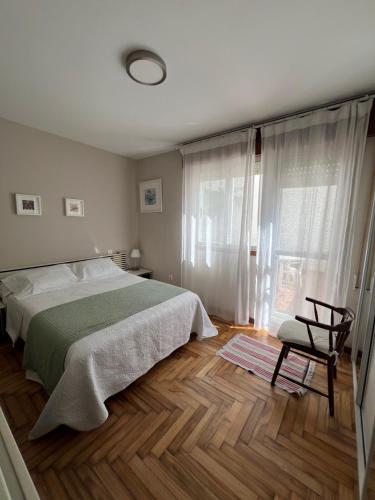 a bedroom with a bed and a chair and a window at La de Mondi in Baiona
