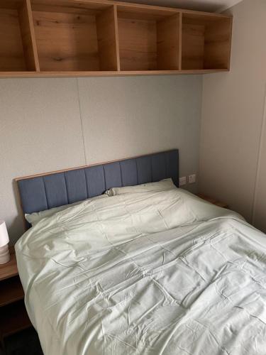 a bed with a blue headboard in a bedroom at Snowdrop Caravan in Porthmadog