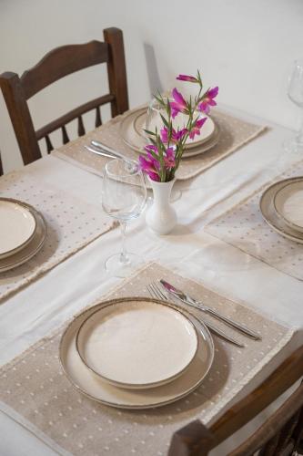 a table with plates and a vase with flowers on it at Galinos traditional house A in Eresos