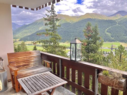 a wooden bench on a balcony with a view of mountains at Chesa Flurigna - Zuoz in Zuoz