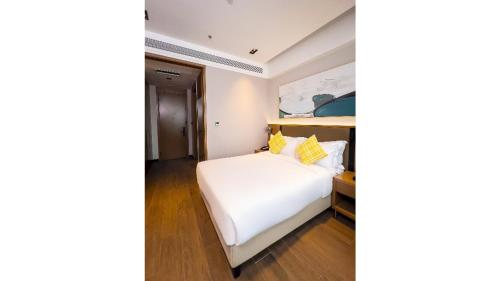 a bedroom with a white bed and a painting on the wall at Golden Tulip Kin-Oasis Kinshasa in Kinshasa