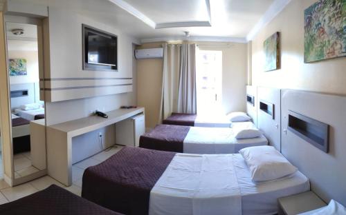 a hotel room with three beds and a mirror at Hotel Joaçaba in Joaçaba