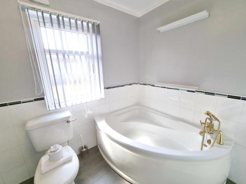 a white bathroom with a tub and a toilet at Birch 25 in Garton