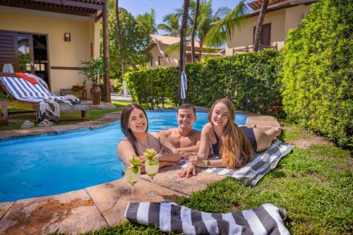 three people sitting next to a swimming pool at Serhs Villas Da Pipa Hotel in Pipa