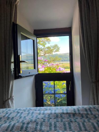 a bedroom with a bed and a window with a view at Coach House, Gogarth in Machynlleth