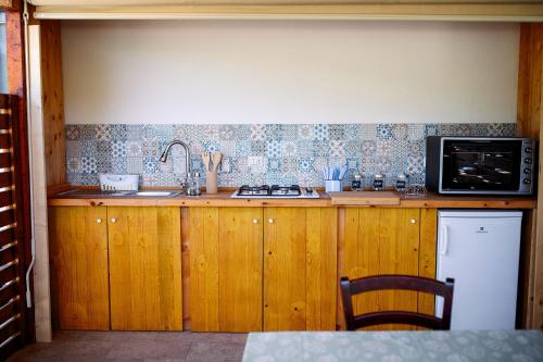 a kitchen with a sink and a stove and a microwave at Limora' Tenuta Millaci in Mazzarino