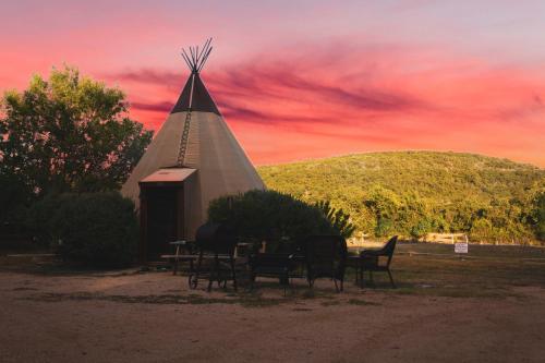 a group of chairs and a church with a sunset at Tipis on the Guadalupe in New Braunfels