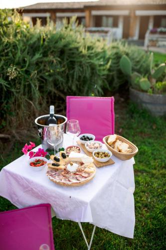 a white table with food on it with pink chairs at Limora' Tenuta Millaci in Mazzarino