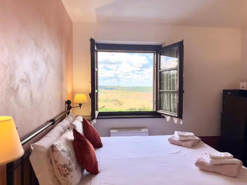 a bedroom with a large bed with a window at AFFITTACAMERE Casale Le Civette in Montepulciano