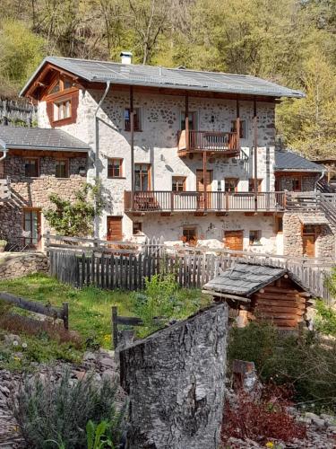 a large stone house with a porch and balcony at Maso La Marianna Bubble Glamping in Trentino in Sant'Orsola Terme