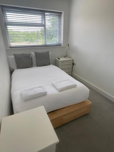 a white bed in a room with a window at Blue House in Stone Grove