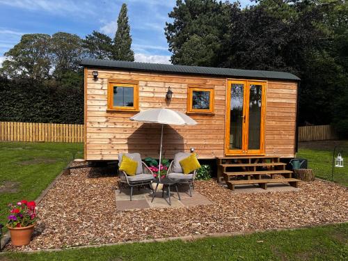 a tiny house with two chairs and an umbrella at Hut in the hall in Bedale