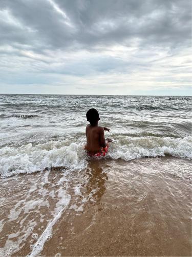 a young boy sitting in the water at the beach at Verb View 6 Berth Caravan St Osyth Clacton-On-Sea in Saint Osyth