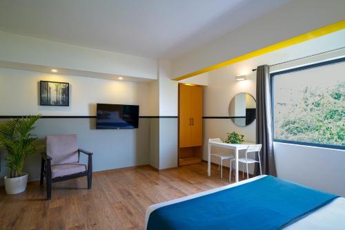 バンガロールにあるOlive Hotel Indiranagar by Embassy Groupのベッドと椅子とテーブルがあるホテルの部屋