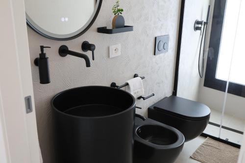 a bathroom with a black tub next to a toilet at DR Luxury Apartments in Avola