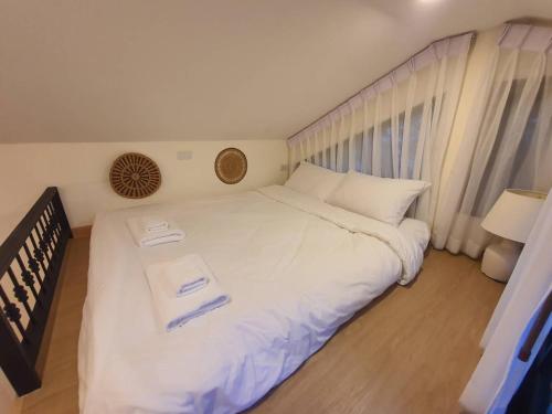 a bedroom with a large white bed with two towels on it at Nordika Hill in Pak Chong