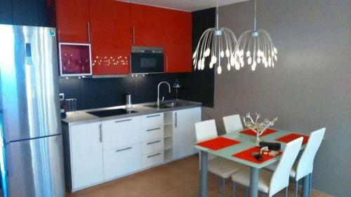 a kitchen with red cabinets and a table with white chairs at Duplex vue Océan in Costa de Antigua