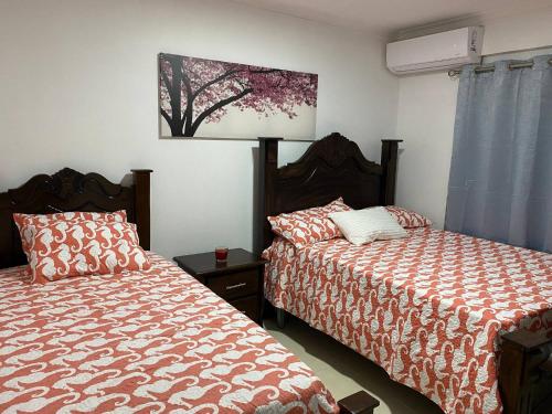 a bedroom with two beds and a painting on the wall at Best location Big 3 Bdrs, Fully Stocked and A/C in Ensanche Quisqueya