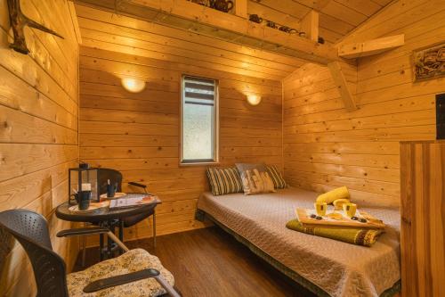ヴェンツピルスにあるKempings Vīnkalniのベッドと机が備わった丸太小屋の寝室