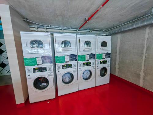 four washing machines are lined up in a laundry room at 2811 SECRT Sabana Hermoso Estudio in San José