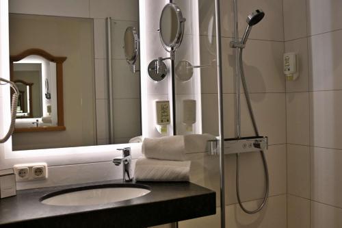a bathroom with a shower and a sink and a mirror at Hotel Zimmerbräu in St. Wolfgang