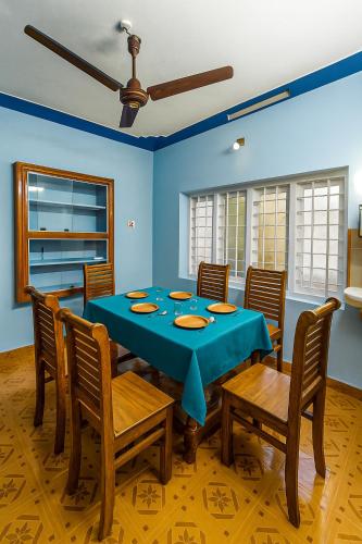 a dining room with a blue table and chairs at Evergreen Homestay in Kollengode