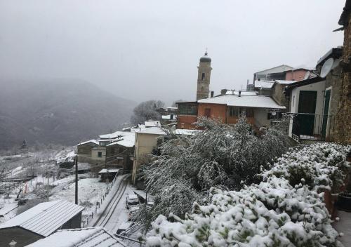 a town covered in snow with a clock tower in the background at Casa di nonno Memé CITRA 008035-LT-0018 in Andagna