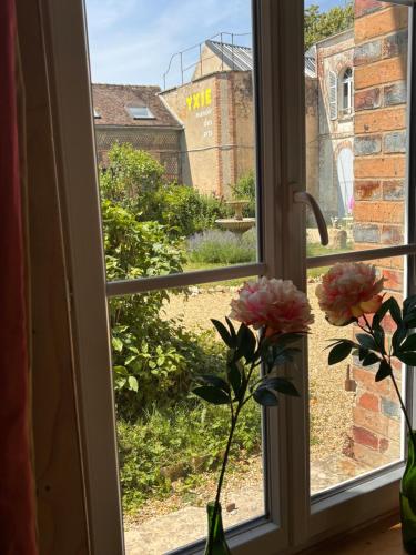 a window with flowers in a vase on a window sill at YXIE - Manoir des Arts in Villeblevin