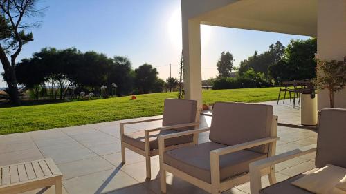 a patio with two chairs and a table and grass at Villa Agapanto in Paestum