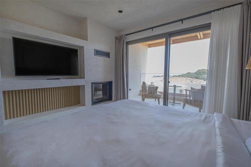 a bedroom with a large bed with a television and a balcony at Radisson Blu Hotel, Kas in Kas
