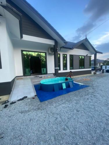 a person playing in a pool in front of a house at Permai Homestay in Kampong Burok