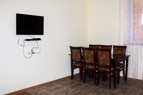 a dining room table with chairs and a television on a wall at Lusya B&B in Yeghegnadzor