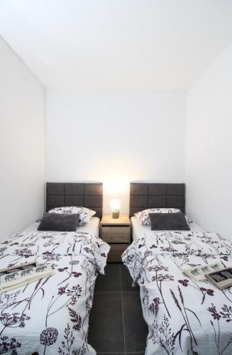 two beds in a room with white walls at Fly in Apartment in Čilipi