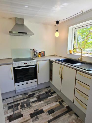 a kitchen with white cabinets and a sink and a window at Irenes Anneks in Nyborg