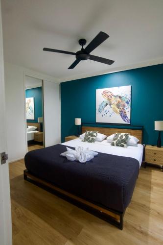 a bedroom with a large bed with a ceiling fan at The Palms At Palm Cove in Palm Cove