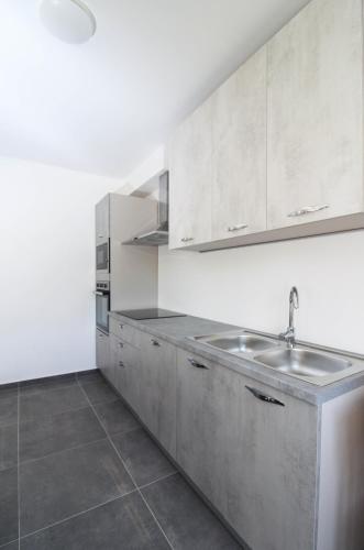 a kitchen with white cabinets and a sink at Fly in Apartment in Čilipi