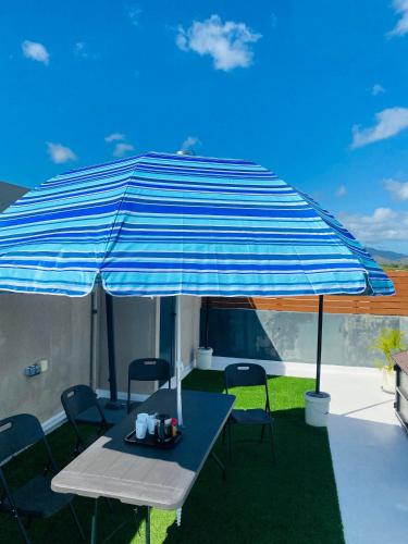 a table and chairs under an umbrella on a patio at Cozy Garden 5 Apartment F1 in Flic-en-Flac