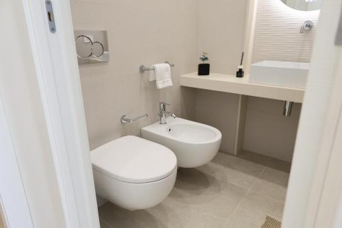 a white bathroom with a toilet and a sink at DR Luxury Apartments in Avola