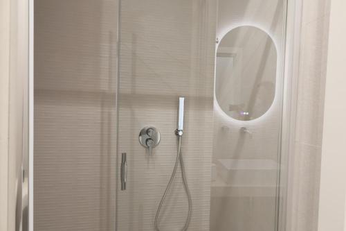 a shower with a glass door with a round mirror at DR Luxury Apartments in Avola